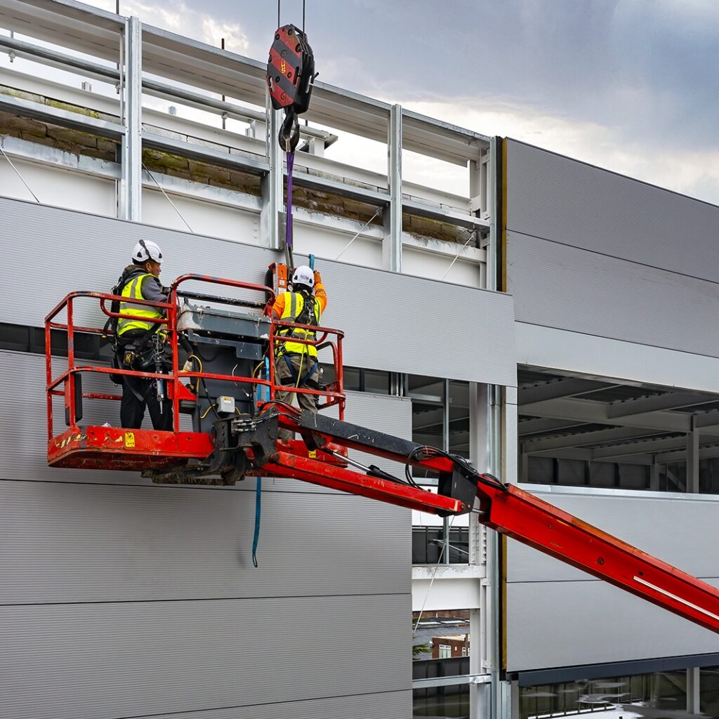 People on cherry picker maintaining cladding